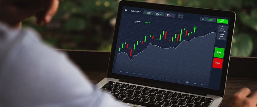 A trader studying their laptop's candlestick charts in search of the best days to trade in the financial markets.