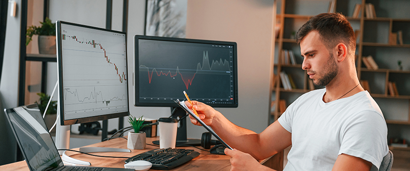 a man sitting behind some screens referring to forex spread trading strategies