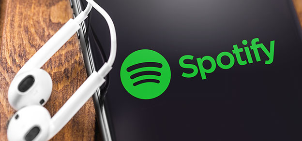 A mobile device with two earphones and the recognizable Spotify logo, representing music streaming and audio content.