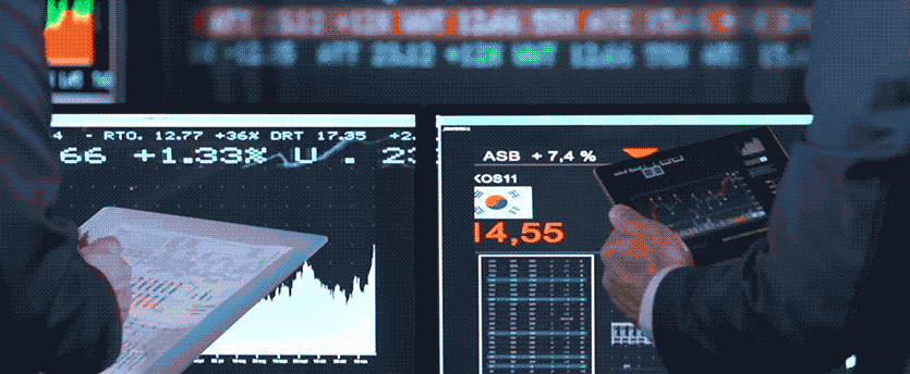 Two brokers in front of monitors displaying live data, representing the world of CFD brokerage and trading.