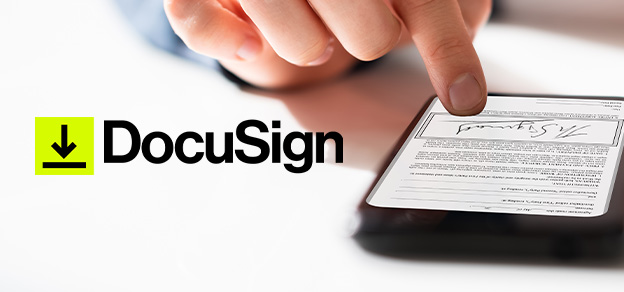 A hand digitally signing on a mobile device with "DocuSign" in front, exemplifying the ease and convenience of electronic document signatures.