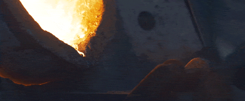 Molten metal being poured into a metal pan.