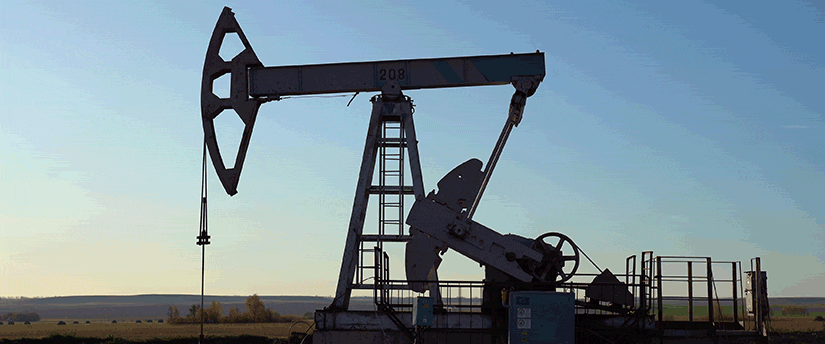 An oil pump stands prominently in a vast field, symbolizing energy production amidst natural surroundings.
