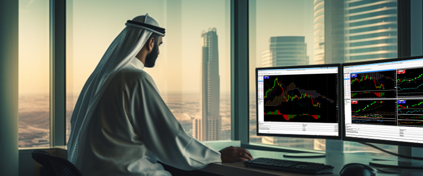 A man in traditional Arabic attire sits at a desk with two monitors showing various trading platforms.