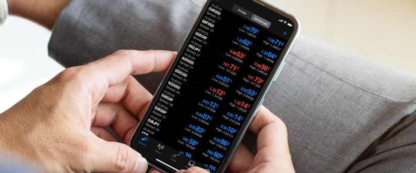 A person using a mobile phone to monitor stock market trading data and charts.