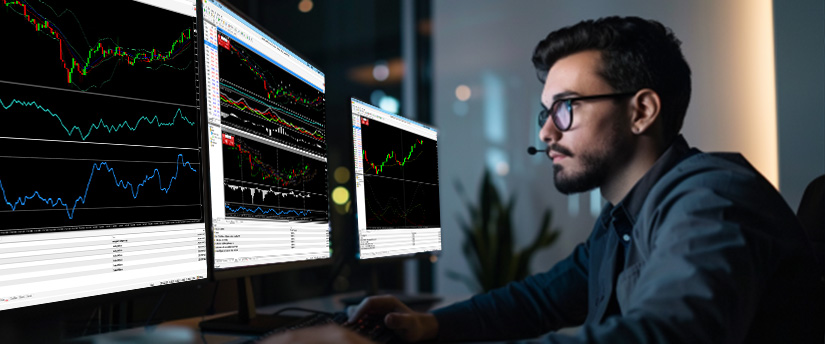 A man at a desk with multiple monitors displaying various forex stock market graphs and data analysis.
