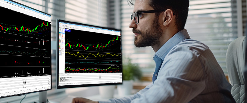  Un hombre con gafas analiza datos de trading de forex mostrados en dos pantallas de ordenador